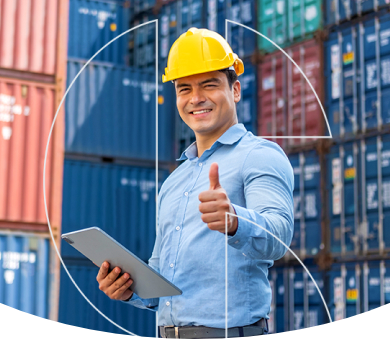 Foto de um homem em frente a containers usando um capacete e segurando uma prancheta e fazendo sinal de positivo com o dedão